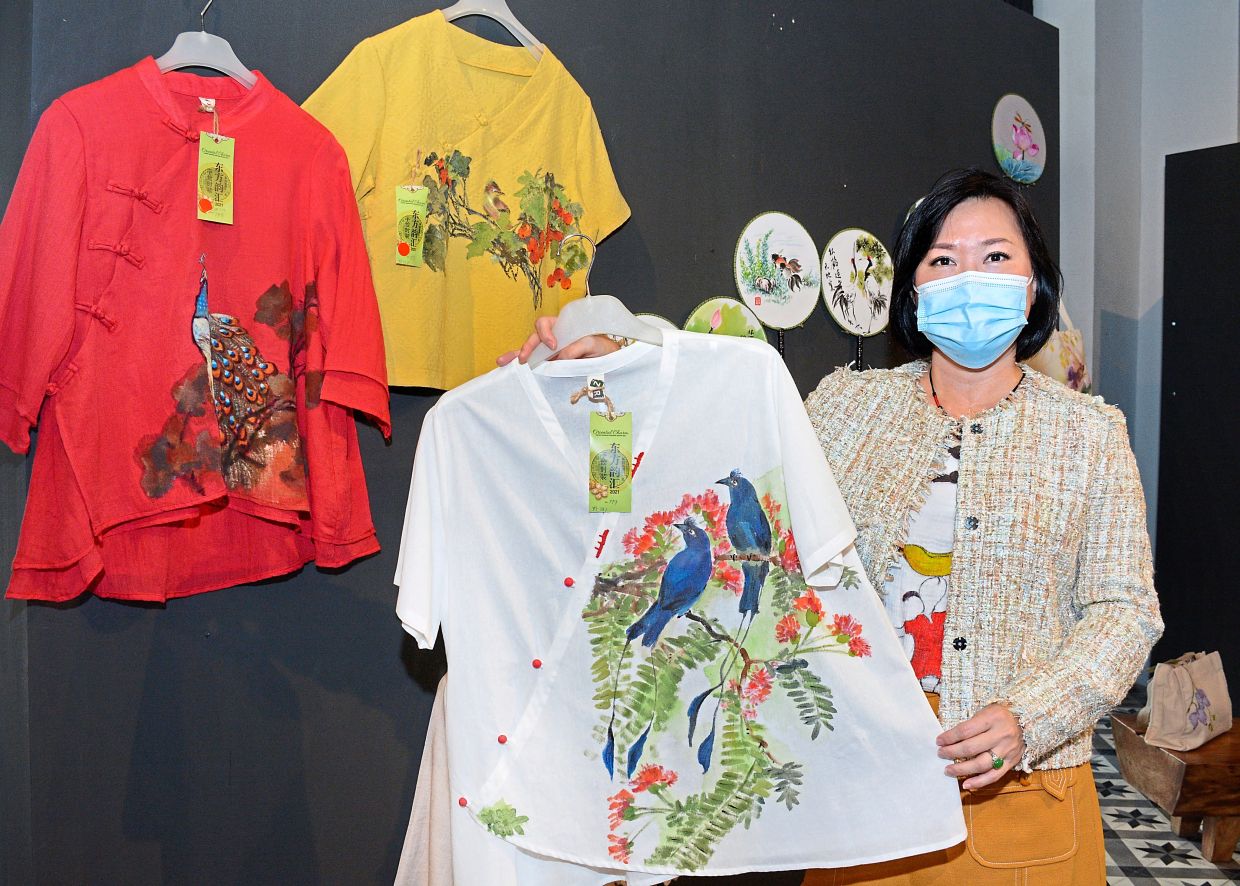 Chinese brush painter and students feature their handiwork on clothing, bags and fans