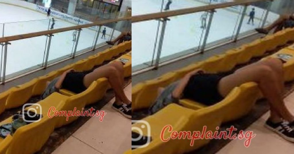 Guy feeling tired, sleep upside down on row of seats in front of ice-skating rink
