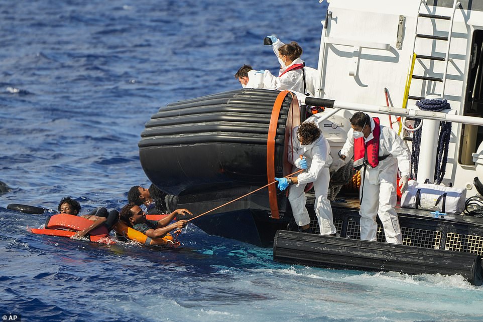 Smiling migrants take selfies as they cross the Med in packed wooden boat - only for their vessel to sink moments later sparking rescue operation off Italian island